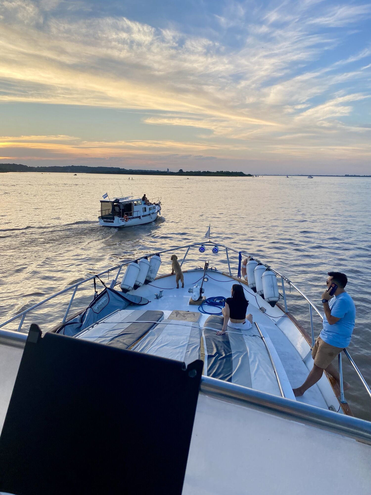 Proa de una embarcación al atardecer en el río Paraná, con otra embarcación navegando adelante